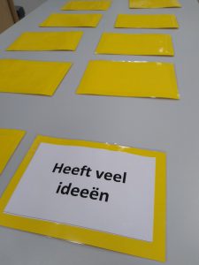 Tafel met omgedraaide kaartjes. Een complimenten kaartje is wel gedraaid en daar staat  op: 'Heeft veel ideeën'.